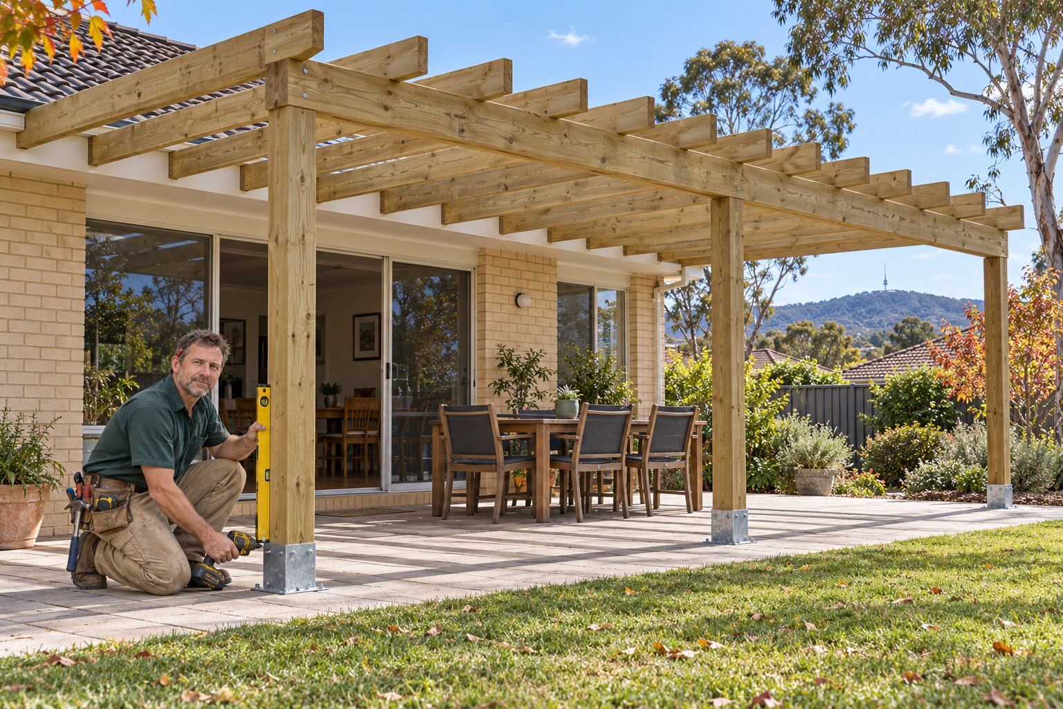 Pergola, Canberra: carpenter checking a post with a spirit level on a new open timber pergola over a patio