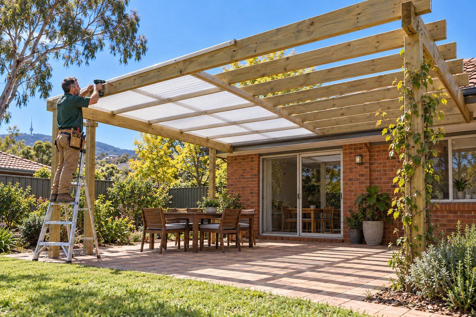 Pergola designs, Canberra: carpenter on a ladder fixing polycarbonate roofing to half of a new timber pergola over a paved patio