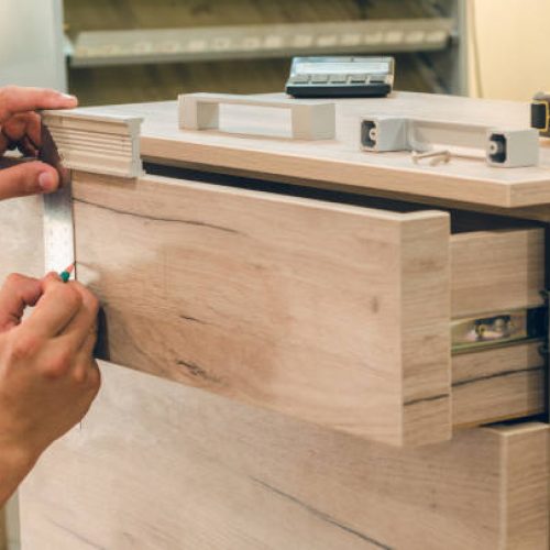 Assembling furniture from chipboard, using a cordless screwdriver, close up.